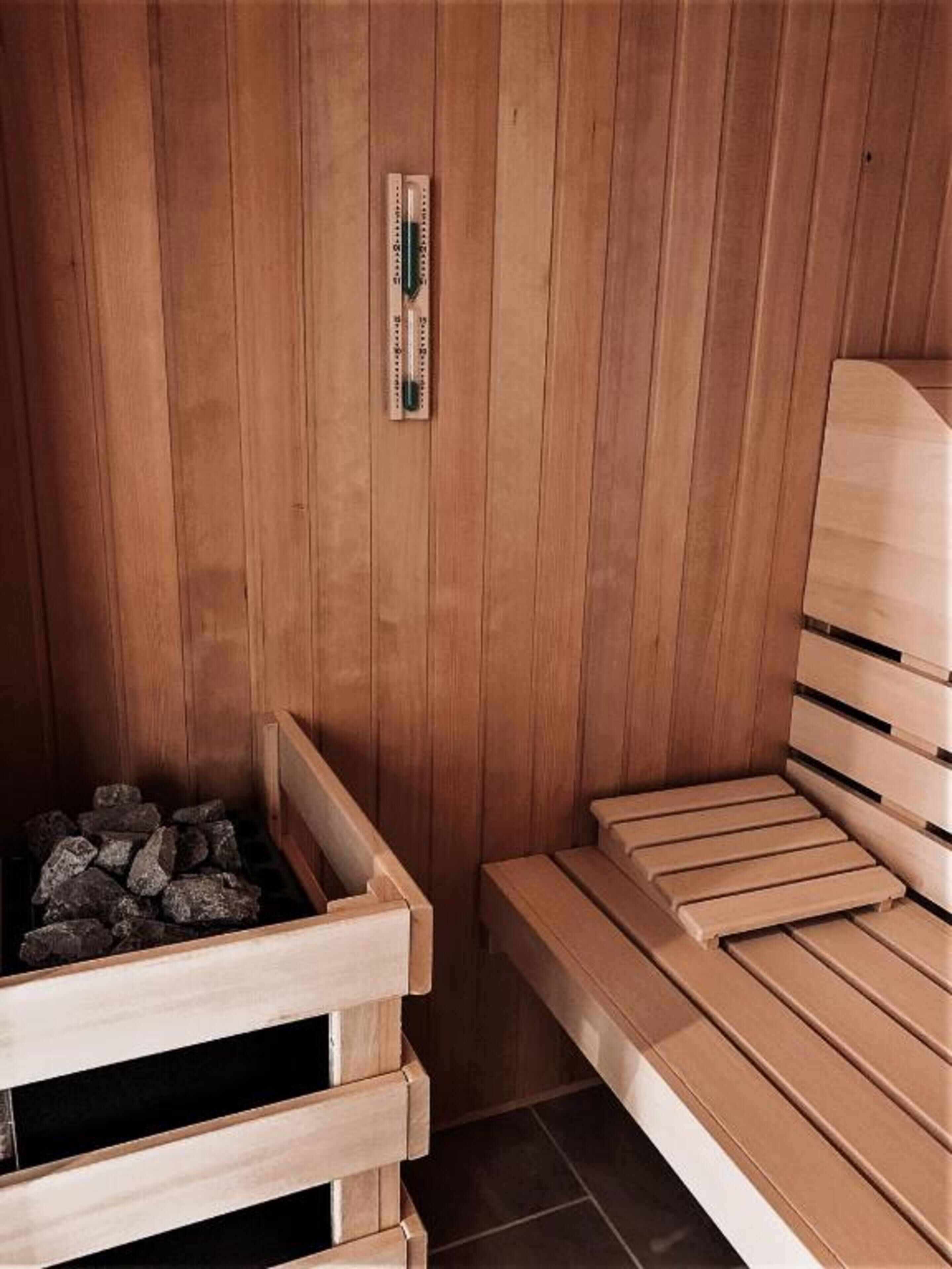 Un sauna en bois, avec des bancs et un thermomètre fixé au mur.