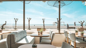 A seaside restaurant with outdoor seating, tables, and chairs, overlooking the beach and ocean. - Hôtel Le Rivage (Chatelaillon-Plage)