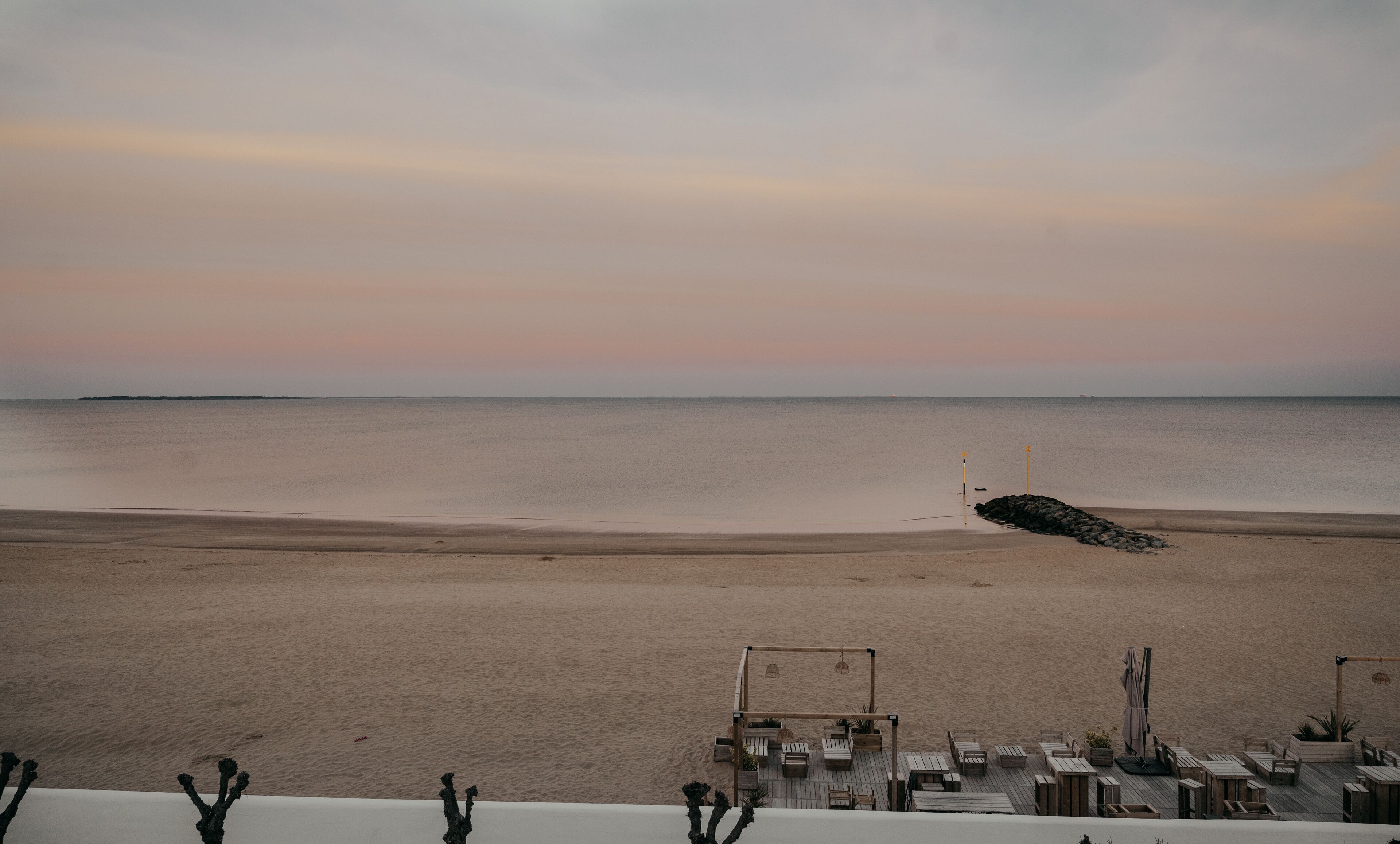 A beach view with a wooden deck area featuring seating and planters.