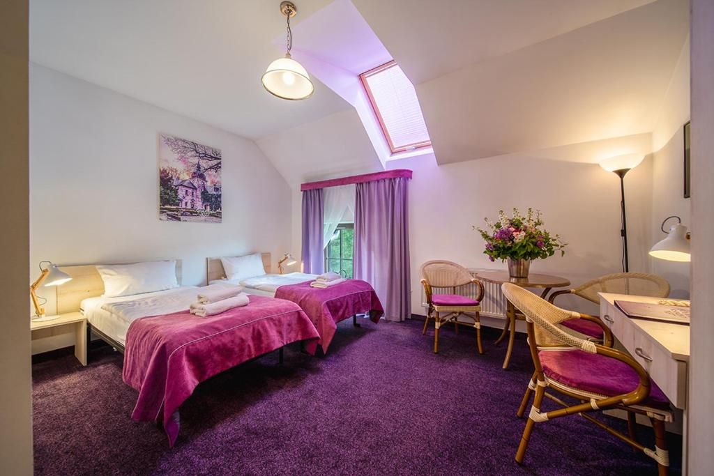 Habitación de hotel con dos camas, un escritorio, una silla, una ventana con cortinas y un cuadro en la pared.