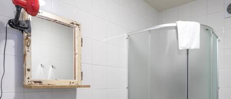 A bathroom with a white sink, a mirror, and a glass shower enclosure.