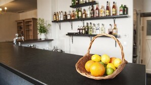 A kitchen counter with a basket of citrus fruits, a sink, and shelves with various bottles. - Folwark Książęcy (Osiecznica)
