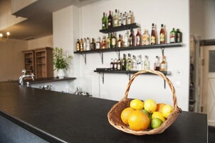 Uma bancada de cozinha com uma cesta de frutas cítricas, uma pia e prateleiras com diversos frascos.