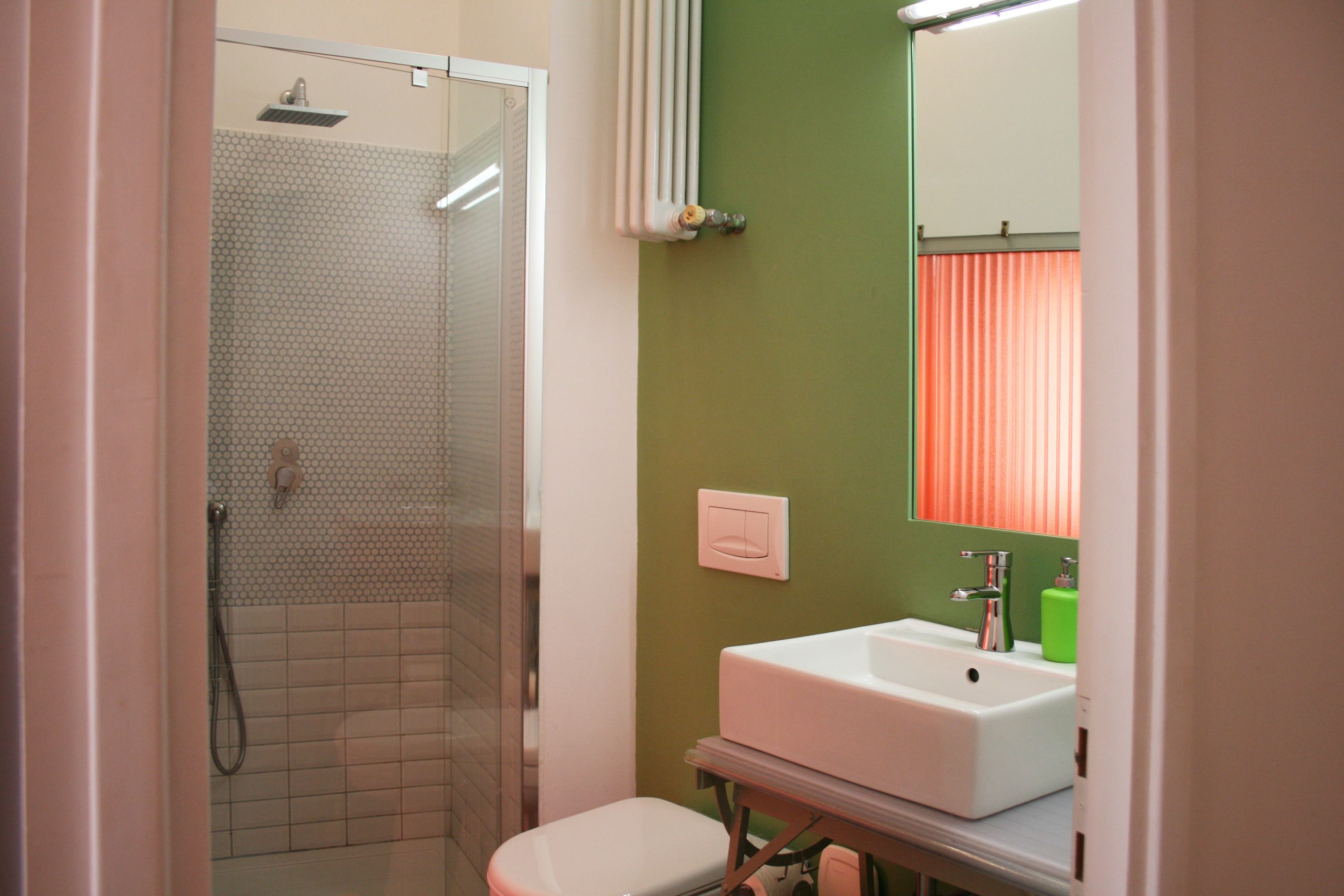 A bathroom with a shower, toilet, sink, and mirror.