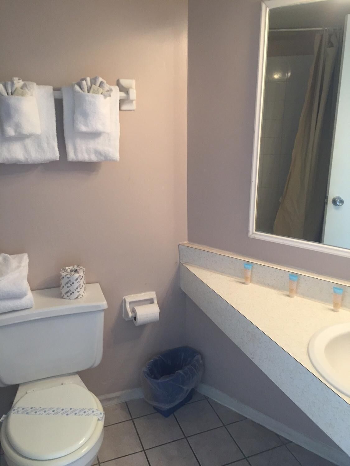 Une salle de bain équipée de toilettes, d’un lavabo, d’un miroir et de deux distributeurs de serviettes.