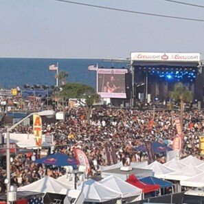 A crowded outdoor event with tents and a stage.