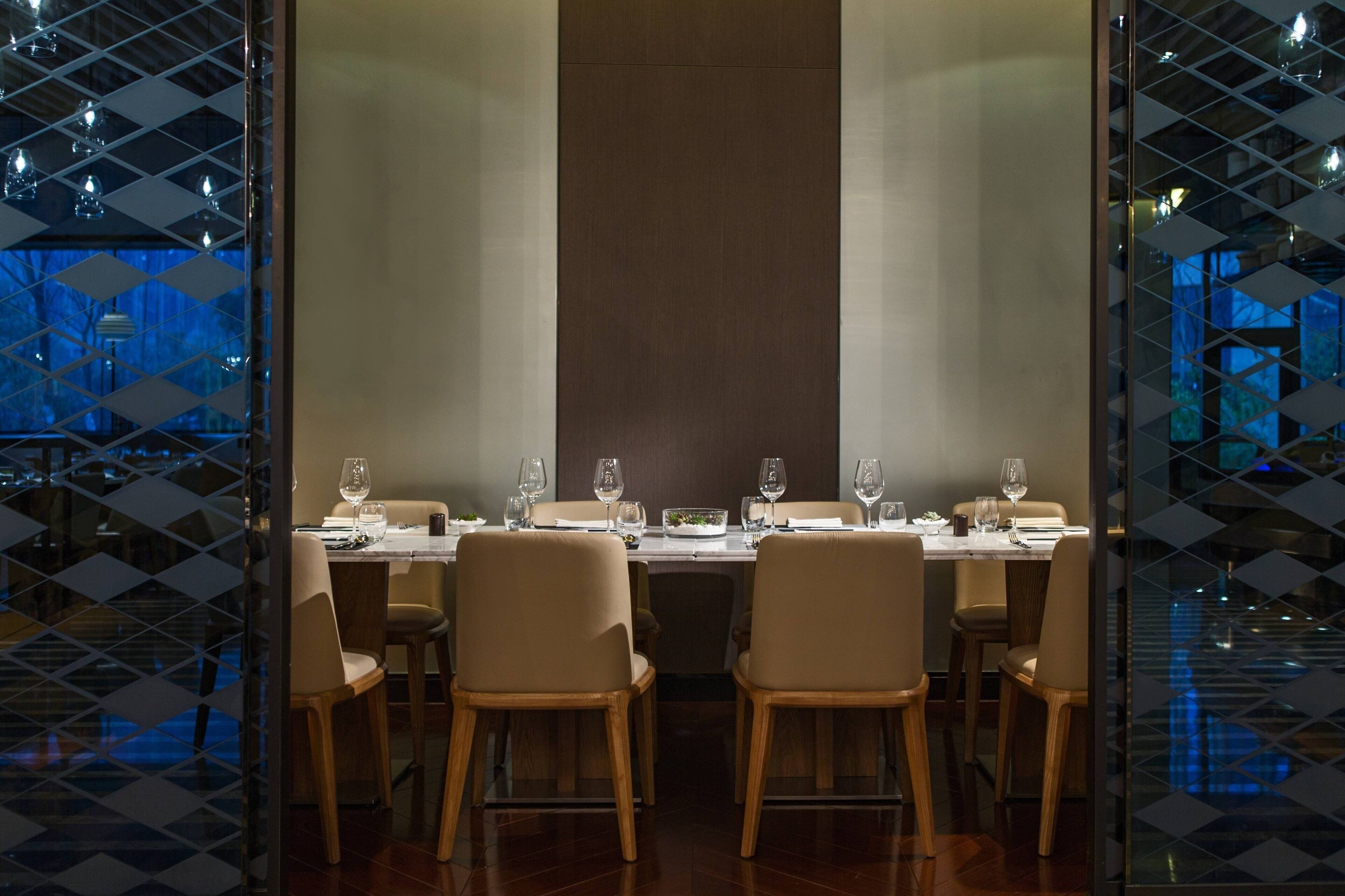 A restaurant with a long table set for a meal, surrounded by chairs.