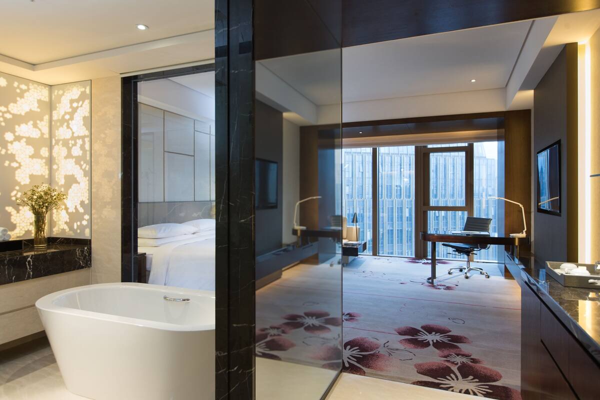 A modern bathroom with a freestanding bathtub, a large mirror, and a floral-patterned shower floor.