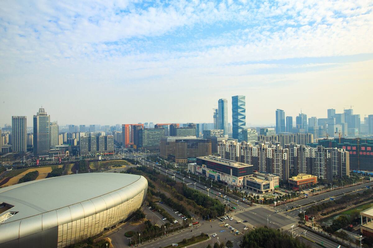 A cityscape with modern high-rise buildings, a large stadium, and a busy intersection.