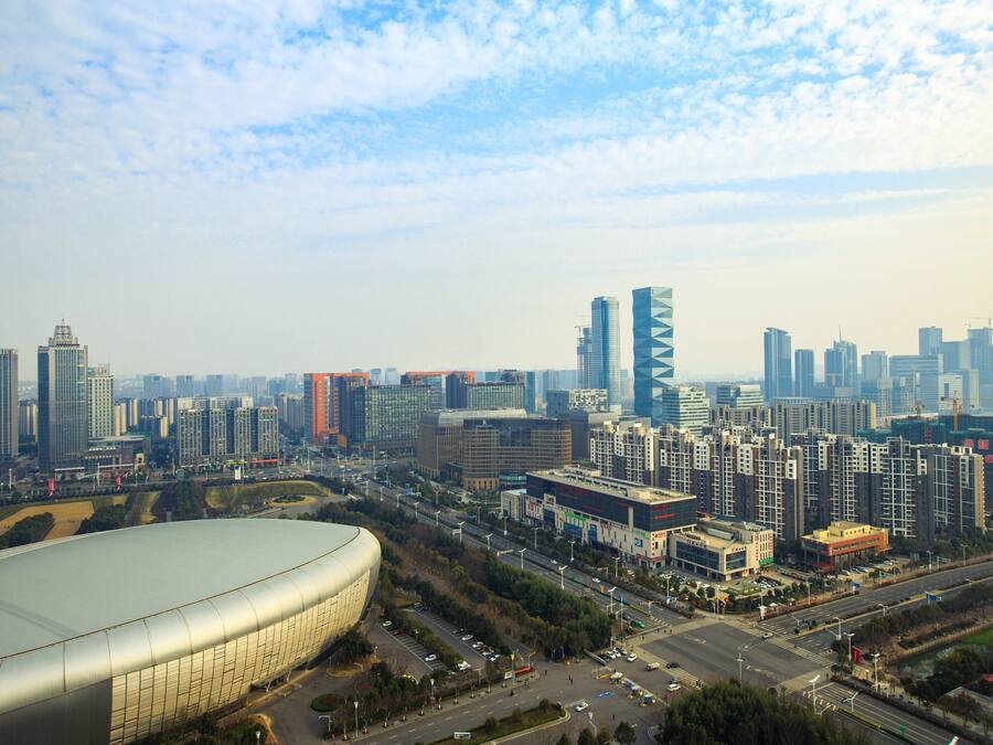 Un paysage urbain avec des immeubles modernes de grande hauteur, un grand stade et un carrefour très fréquenté.