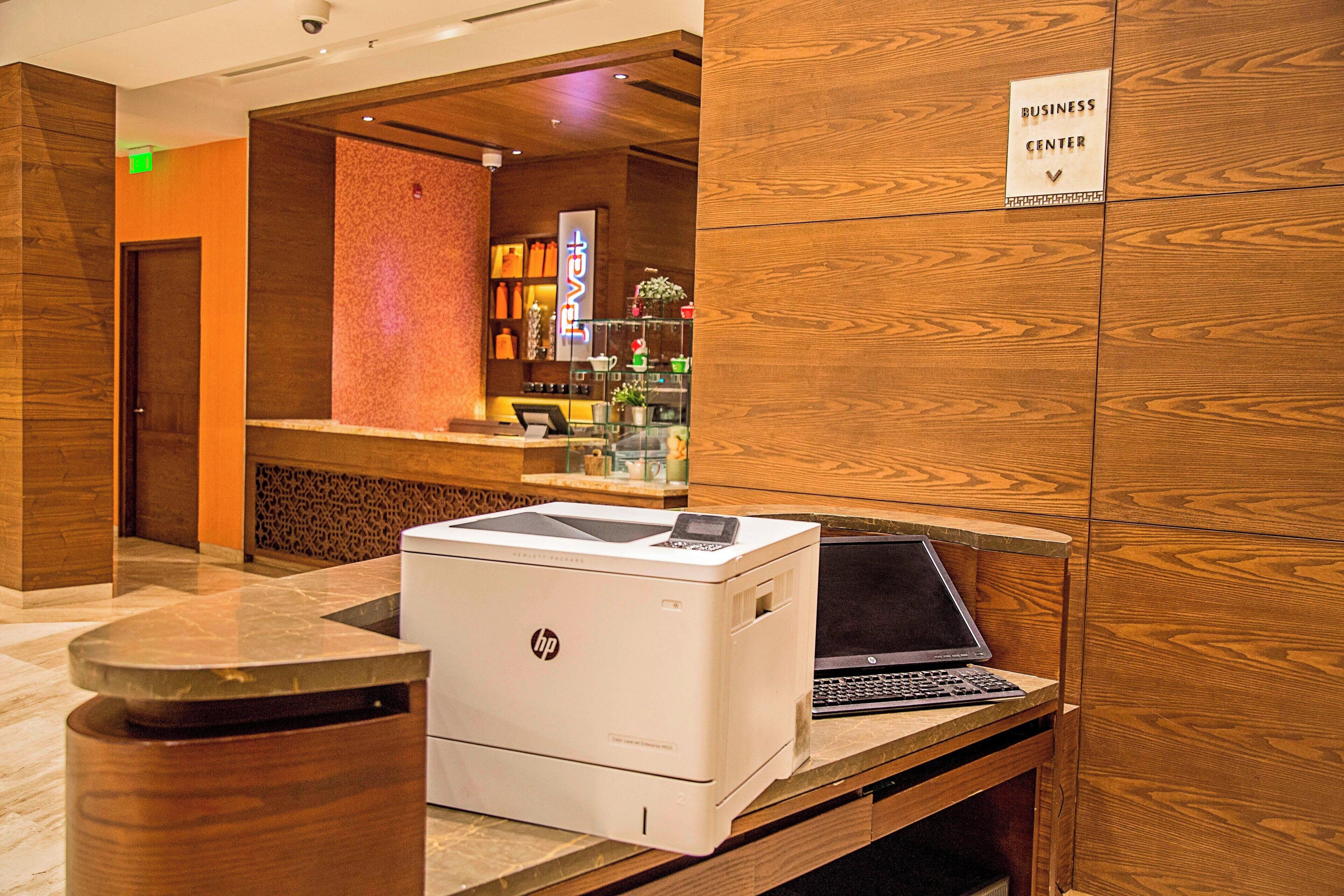 A business center with a printer, a laptop, and a reception desk.