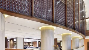 A spacious lobby with a curved seating area, large pillars, and a decorative floor pattern. - Courtyard by Marriott Raipur (Raipur)