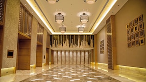 A spacious lobby with a marble floor, decorative wall panels, and hanging lamps. - Courtyard by Marriott Raipur (Raipur)
