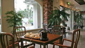 A dining area with a table set for two, surrounded by chairs, with a view of the outdoors through large windows. - SongYuan Hotel (Lugu)