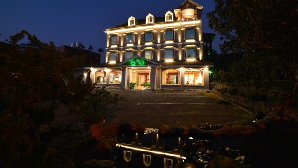 A multi-story hotel with a well-lit facade, large windows, and a green sign indicating the name. - SongYuan Hotel (Lugu)