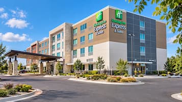Ein Holiday Inn Express & Suites Hotel mit modernem Design, mit überdachter Zufahrt und gepflegten Grünflächen.