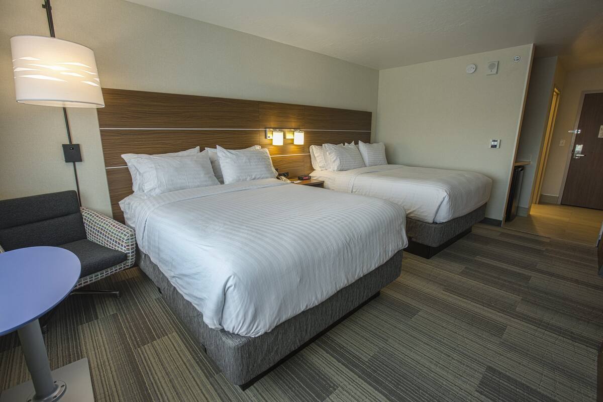 A hotel room with two beds, a desk, and a chair.