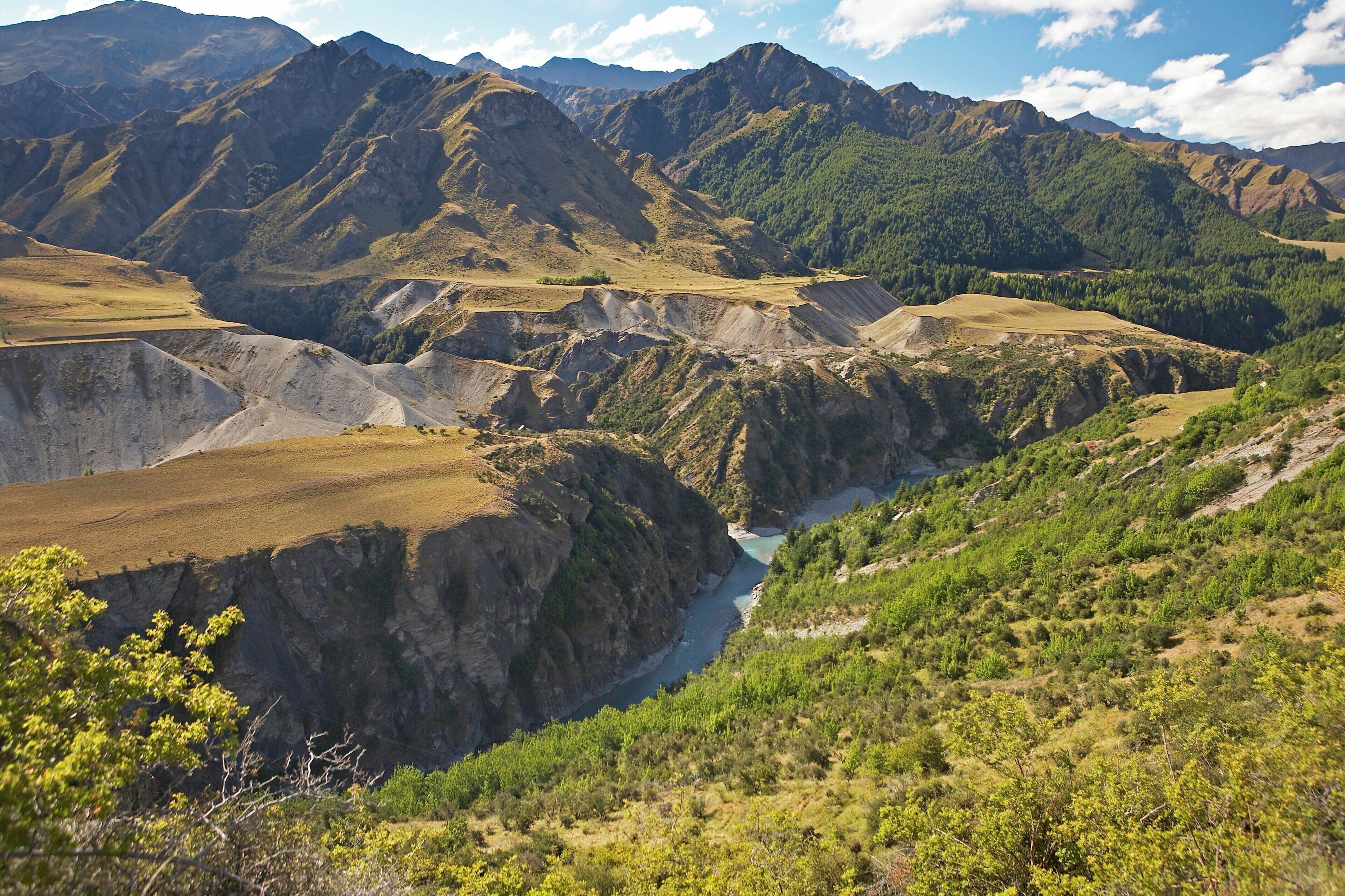 A mountainous landscape with a river valley and forested areas.