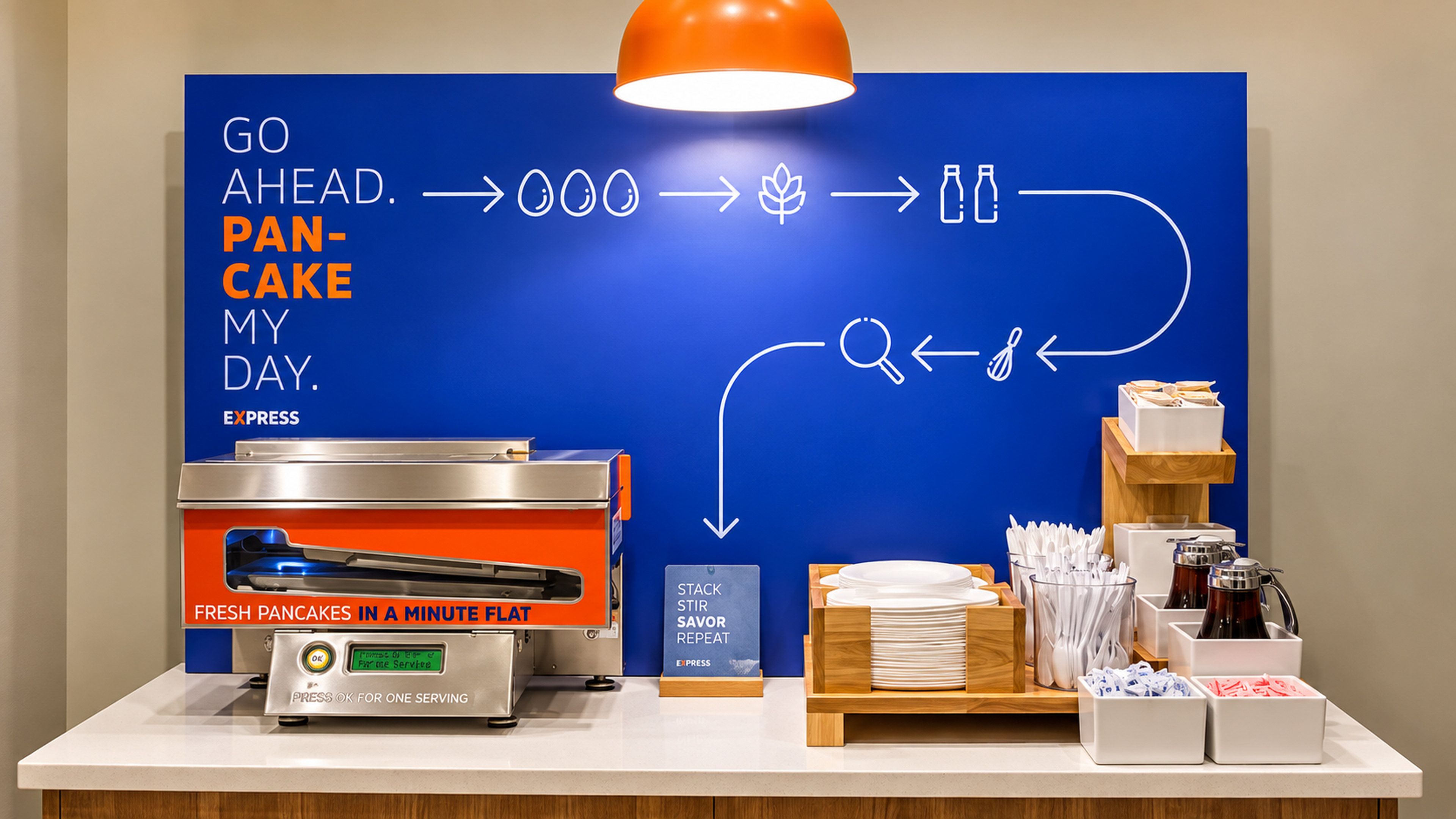 A breakfast station with a flat-top griddle, a stack stir service sign, and a display of breakfast items.