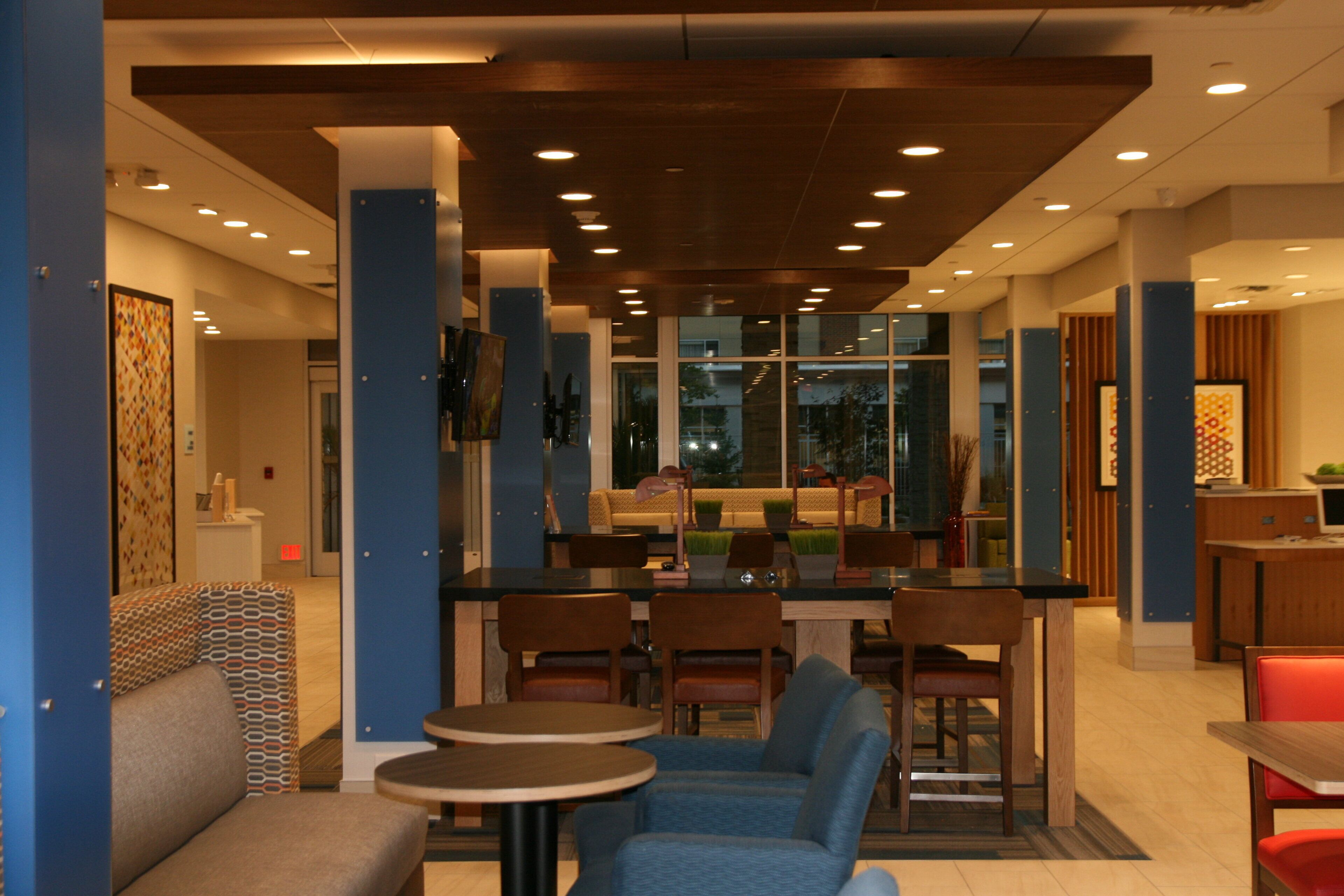 A modern hotel lobby with a bar area, seating arrangements, and a view through large windows.