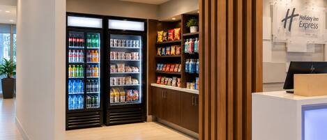 A hotel lobby with a reception desk, a Holiday Inn Express sign, and a refrigerated beverage display.