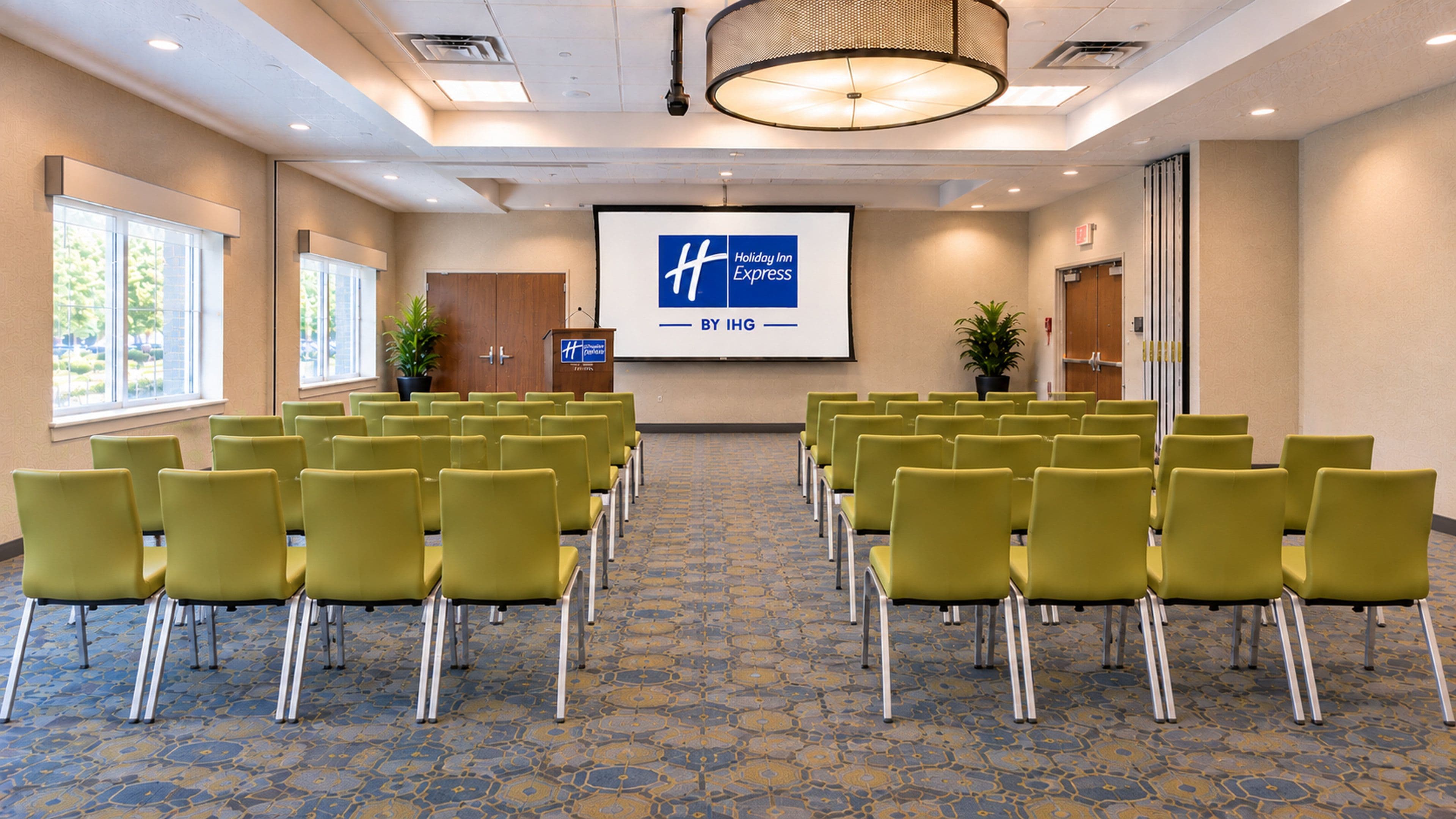 A conference room with rows of chairs, a podium, and a screen displaying the Holiday Inn Express logo.