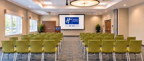 A conference room with rows of chairs, a podium, and a screen displaying the Holiday Inn Express logo.