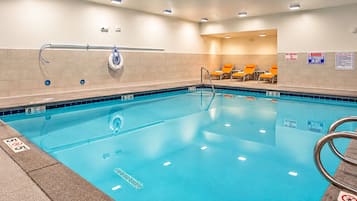Una piscina con borde de azulejos, una silla de salvavidas y un cartel de prohibido bucear.