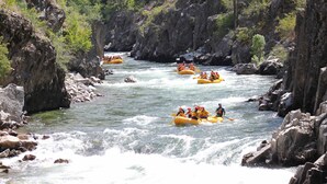 A group of people rafting down a river surrounded by rocky cliffs and greenery. - Holiday Inn Express & Suites Boise Airport by IHG (Boise)