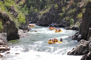 A group of people rafting down a river surrounded by rocky cliffs and greenery. - Holiday Inn Express & Suites Boise Airport by IHG (Boise)