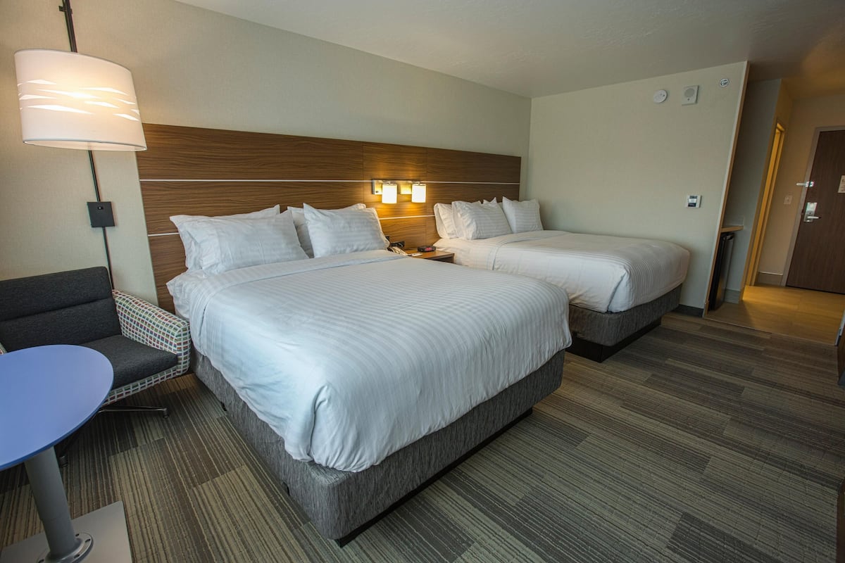 A hotel room with two beds, a desk, and a chair.