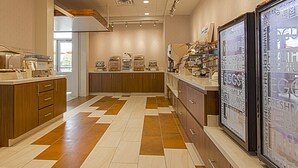 A bakery counter with various baked goods and a refrigerator displaying dairy products. - Holiday Inn Express & Suites Boise Airport by IHG (Boise)