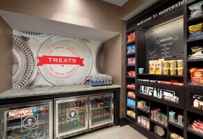 A snack bar with a 'Treats' sign, refrigerated drink dispensers, and shelves stocked with various snacks and beverages.