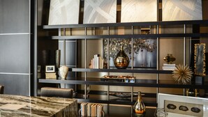 Un interior moderno con una estantería de tonos oscuros que exhibe libros, objetos decorativos y obras de arte enmarcadas.