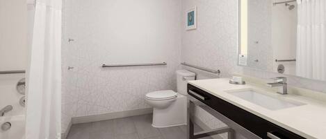 Une salle de bain moderne avec des toilettes blanches, un lavabo avec un miroir et un espace douche.