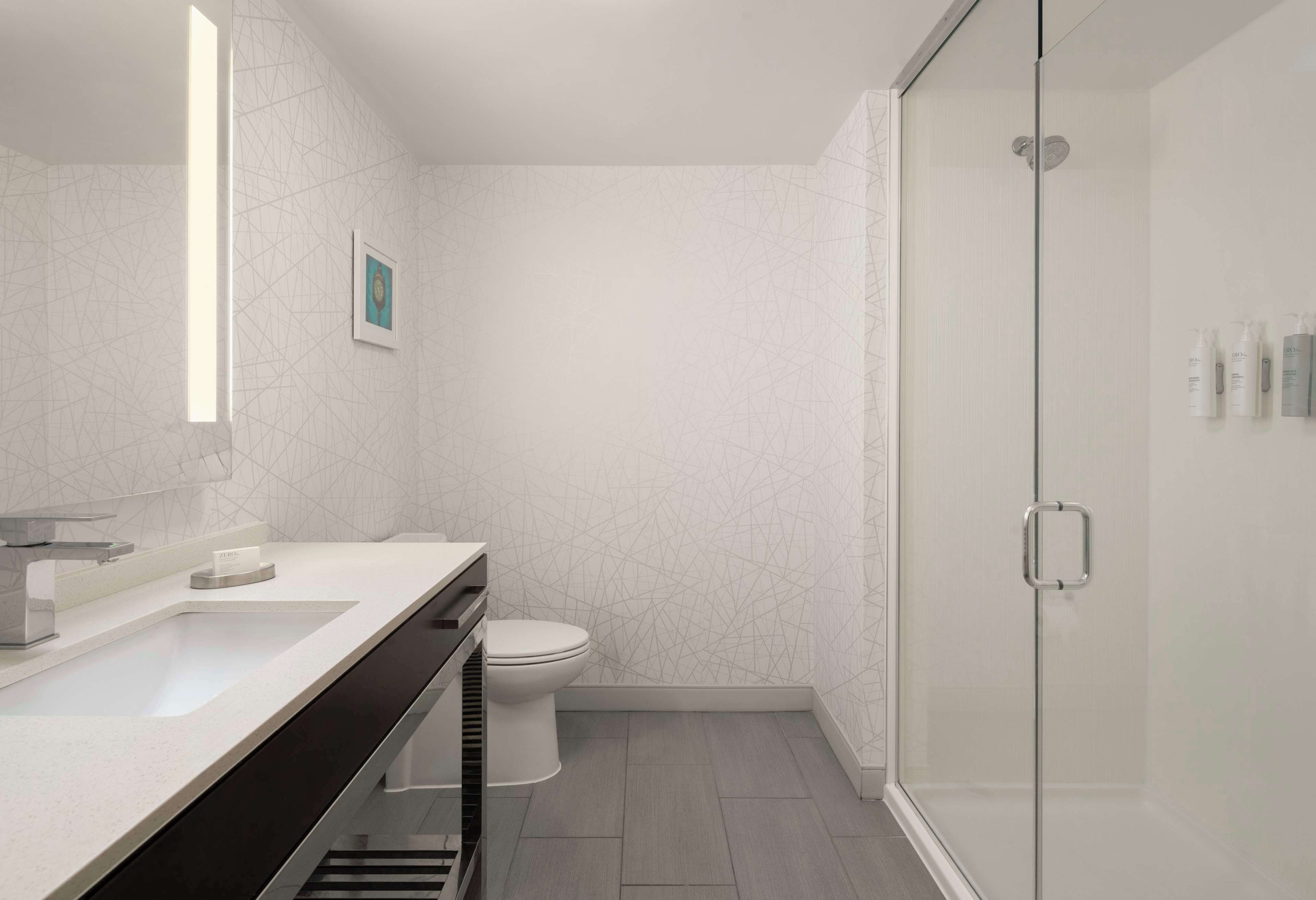 A modern bathroom with a glass shower enclosure, a white toilet, and a vanity with a sink and mirror.