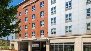 Un hôtel Hampton Inn & Suites à la façade en briques, doté de grandes fenêtres et d’une entrée abritée.