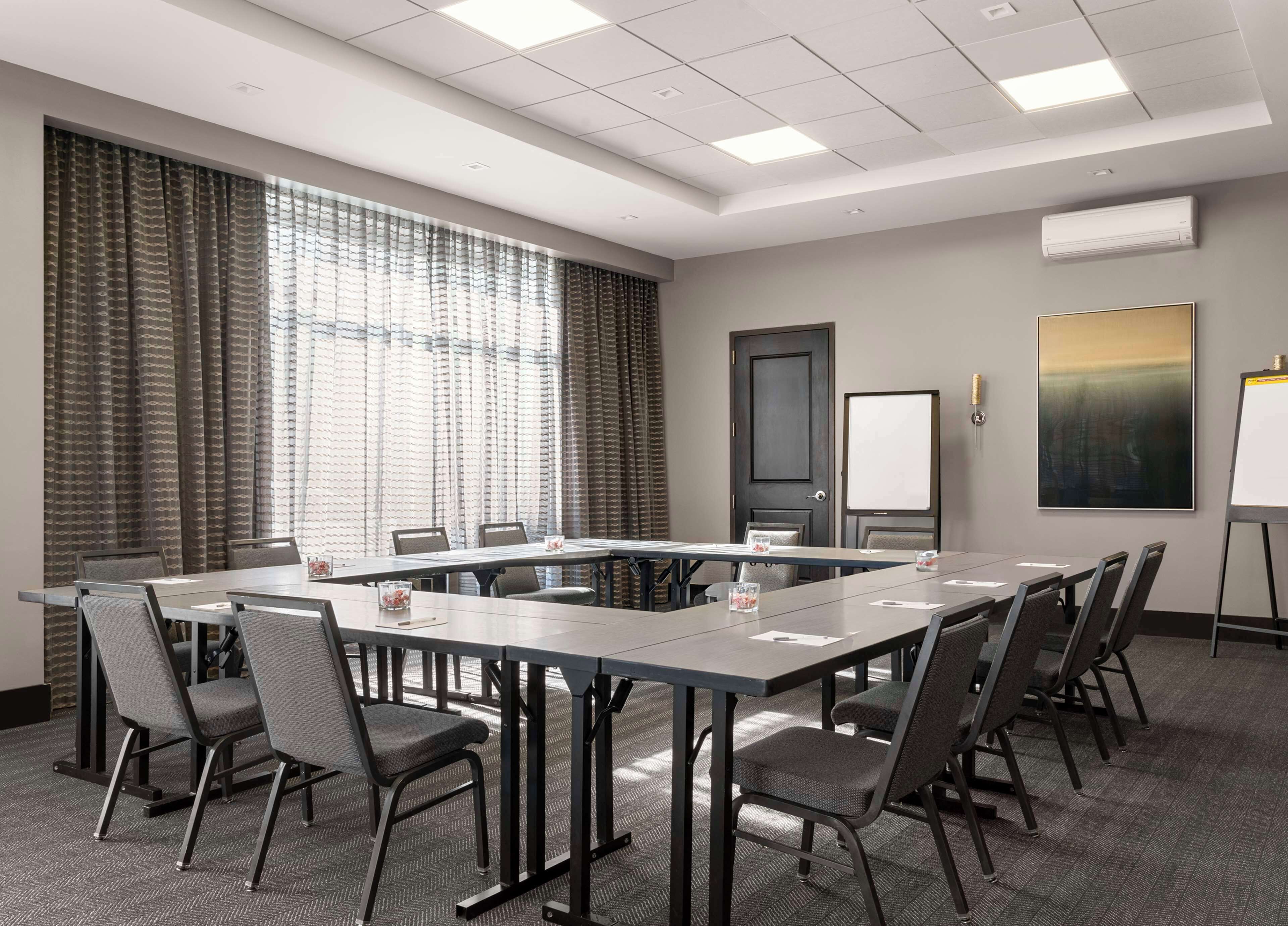 A conference room with a large table, chairs, a whiteboard, and a painting on the wall.