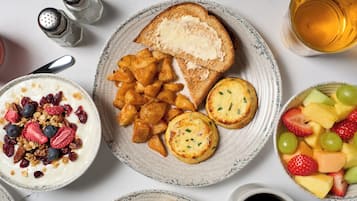 Een ontbijttafel met toast, fruit, yoghurt en een kopje thee.