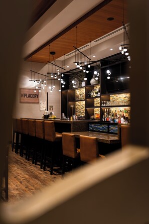 A bar area with a counter, stools, and hanging lights. - Hyatt Place Washington DC/Georgetown/West End (Washington)