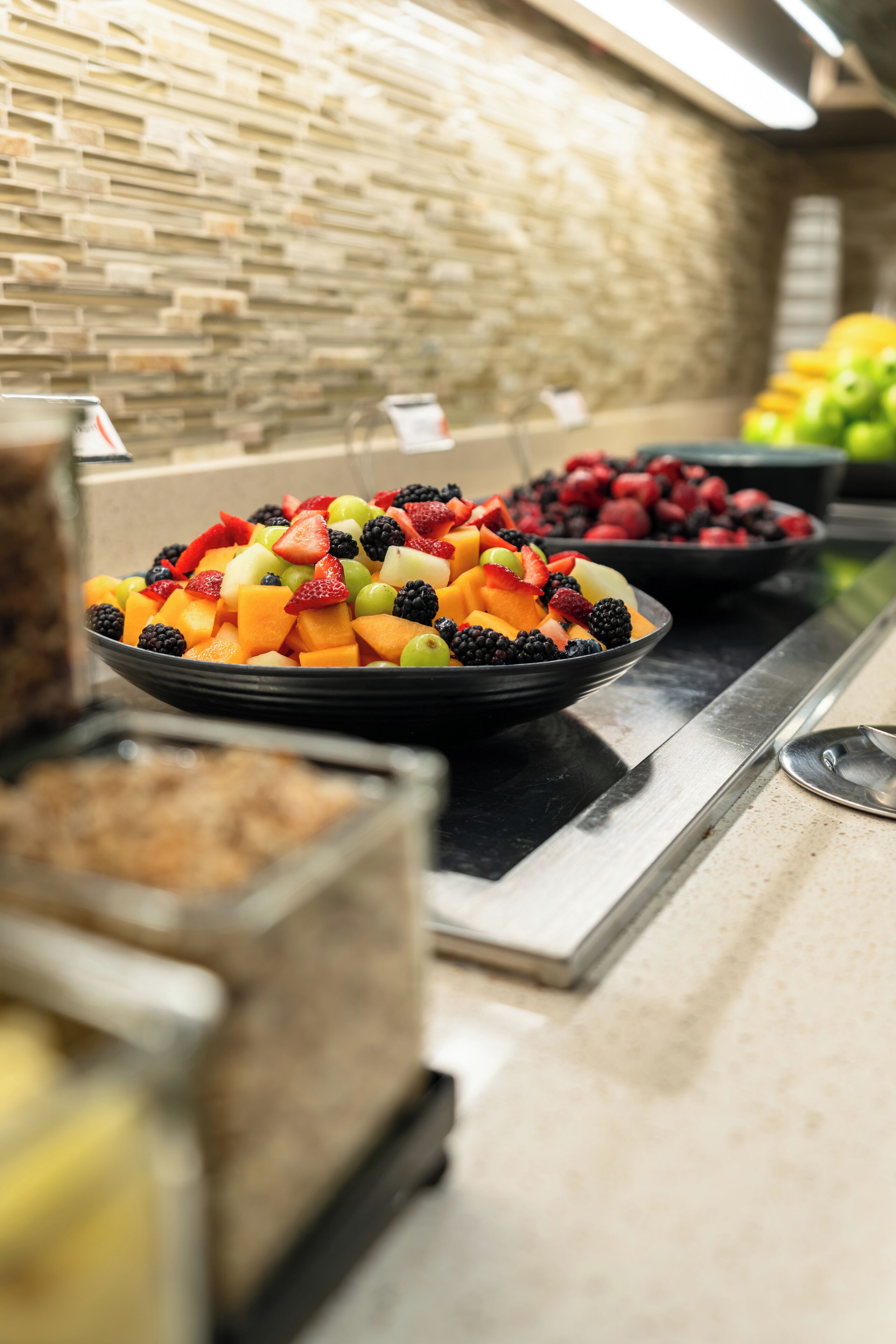 Un buffet garni de divers fruits, avec un mur de pierres en arrière-plan.