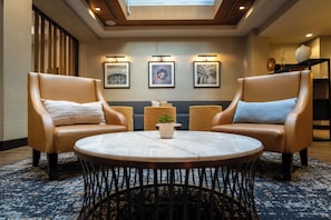 A modern lounge area with leather armchairs, a round table, and framed artwork on the wall. - Hyatt Place Washington DC/Georgetown/West End (Washington)