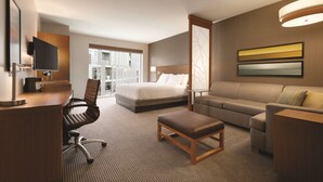 A hotel room with a bed, a sofa, a desk with a chair, a television, and a large window with a view. - Hyatt Place Washington DC/Georgetown/West End (Washington)