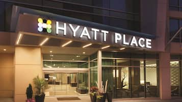 Die Außenansicht eines Hotels im modernen Stil, mit einem gut sichtbaren 'HYATT PLACE'-Schild und einem Glastür.