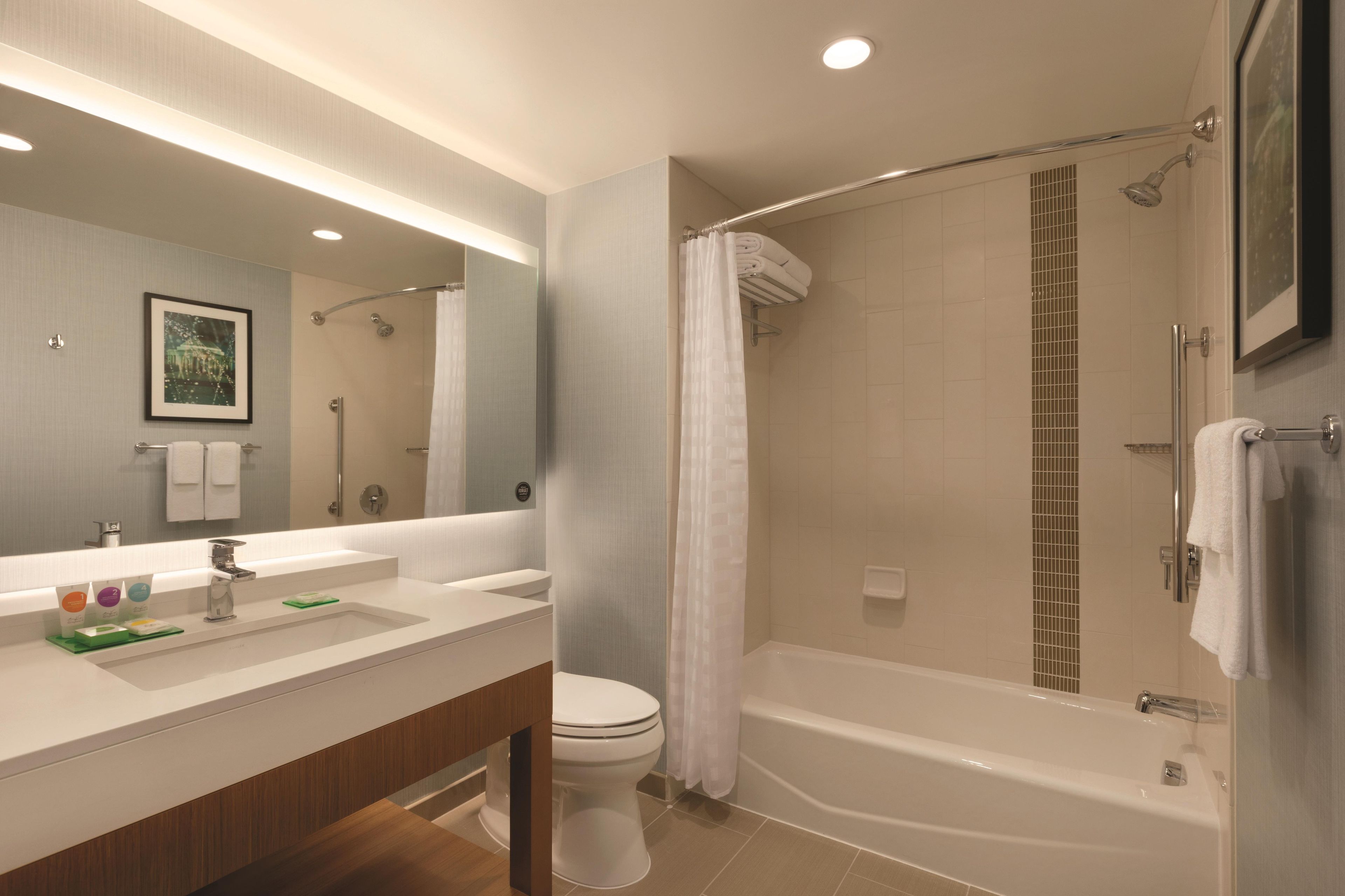 Un baño moderno con un espejo grande, una bañera y una ducha.