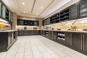 A modern kitchen with dark cabinetry, a tiled floor, and a built-in coffee station.