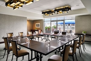 A conference room with a long table, chairs, and a modern ceiling light fixture.