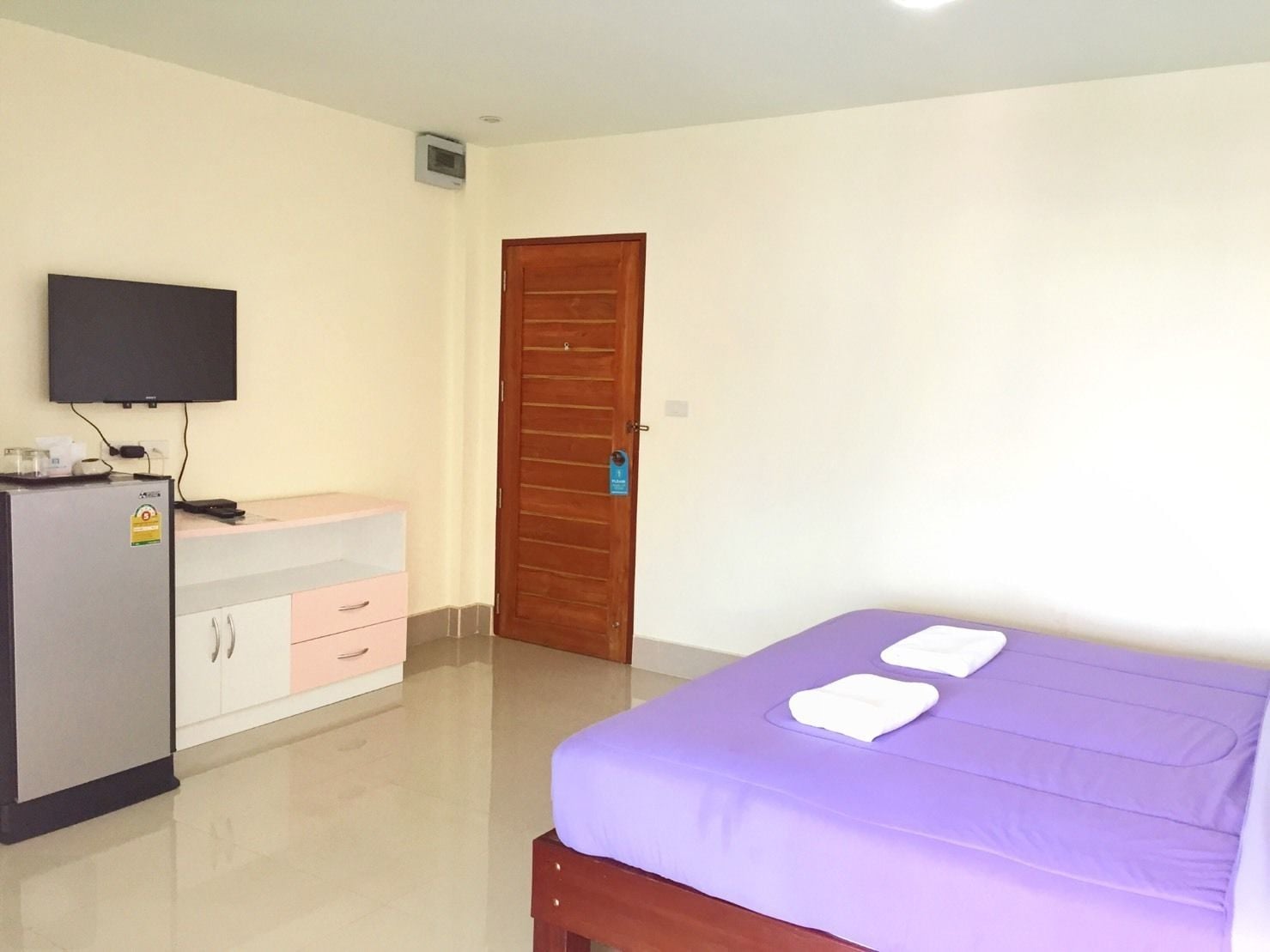 A hotel room with a bed, a desk with a computer, a television, and a wardrobe.