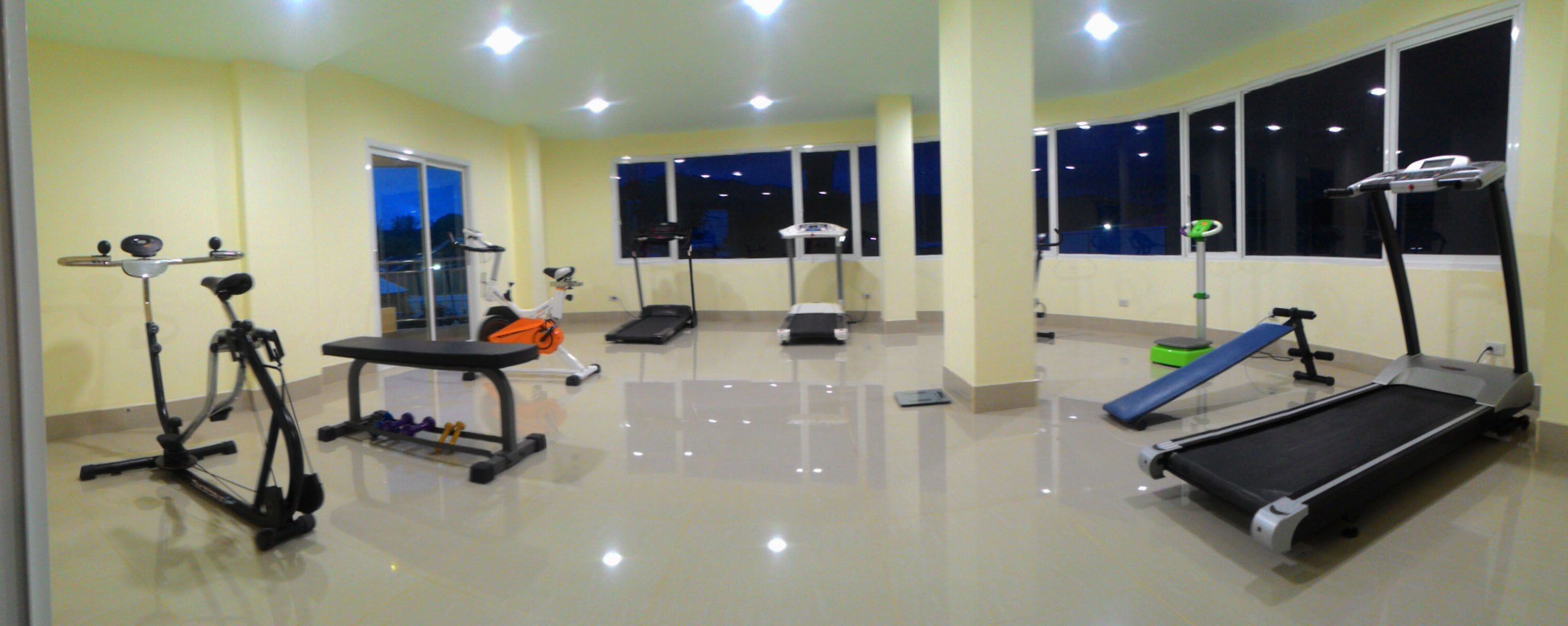 A gym with various exercise equipment including treadmills, an elliptical, and a stationary bike.