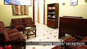 A hotel reception area with a sofa set, a coffee table, a bookshelf, and a television on the wall. - Hostel Vienna (Cairo)